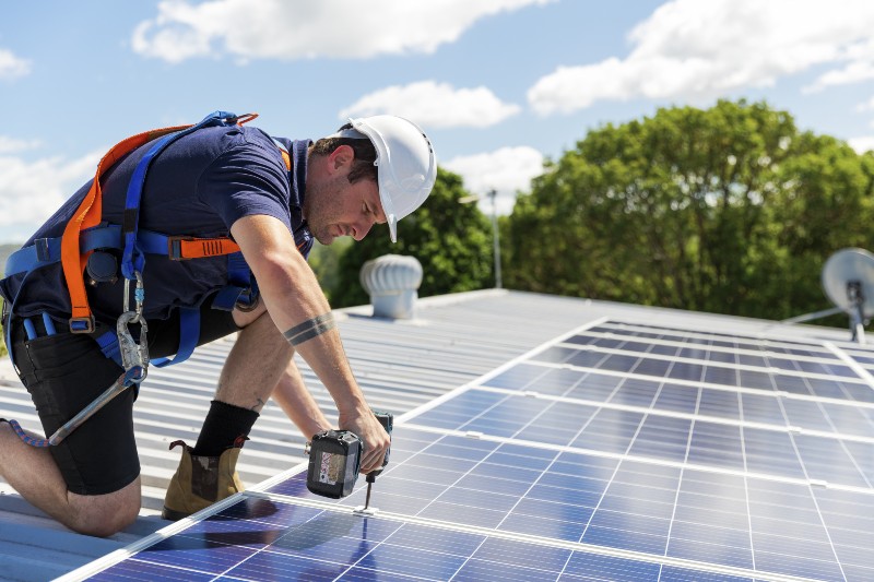 man installing solar panels on roof